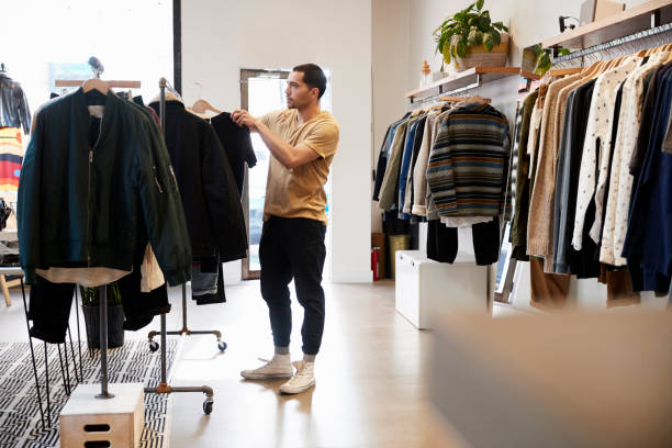 Young Hispanic man looking at clothes on a rail in a shop